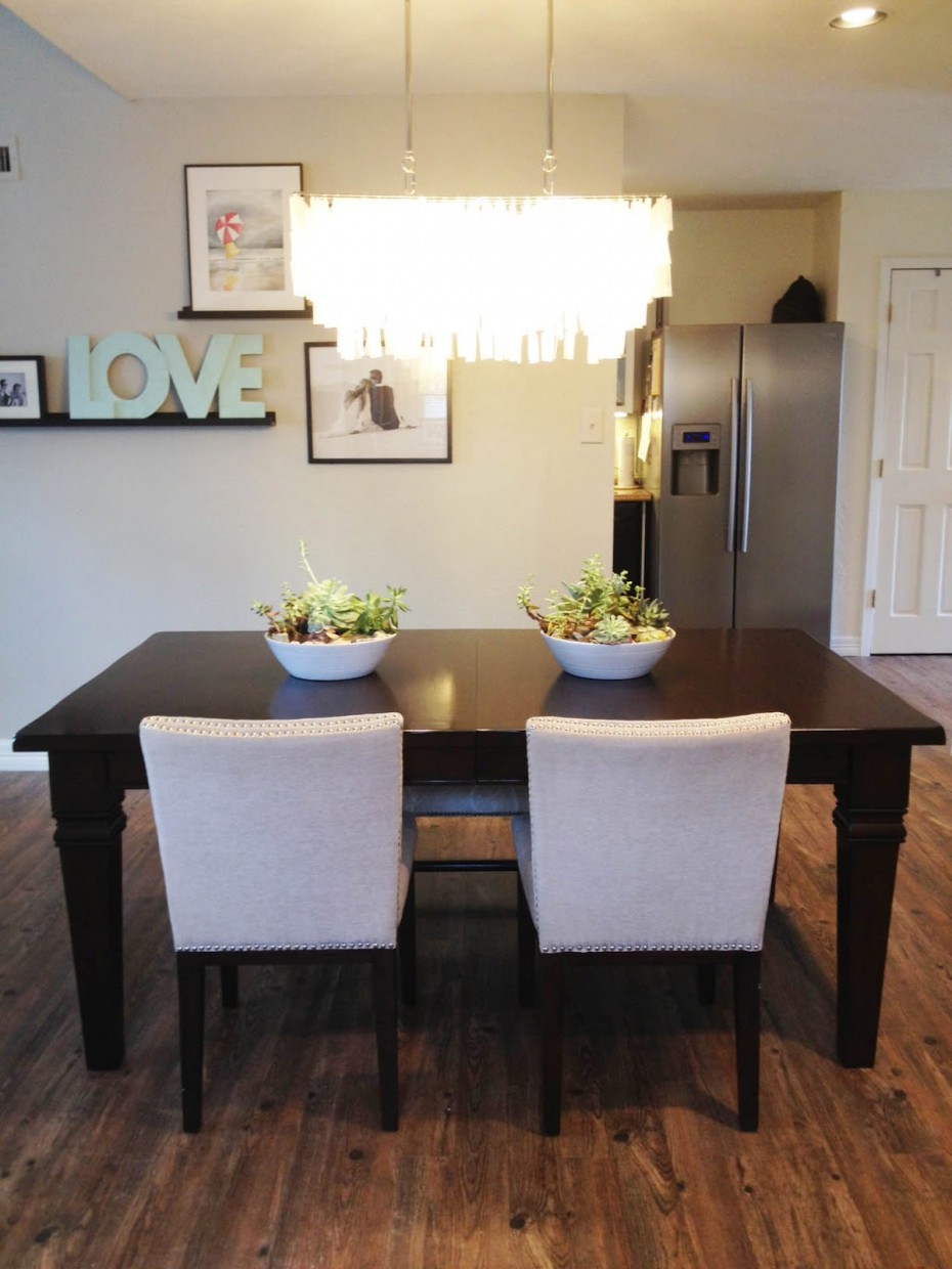 Brilliant Glass Dining Room Chandeliers Over Glorious Wooden Dining Table Also Two White Fabric Armless Chairs On Wooden Flooring Installation Also Nice Pictures Attach On White Wall Decoration