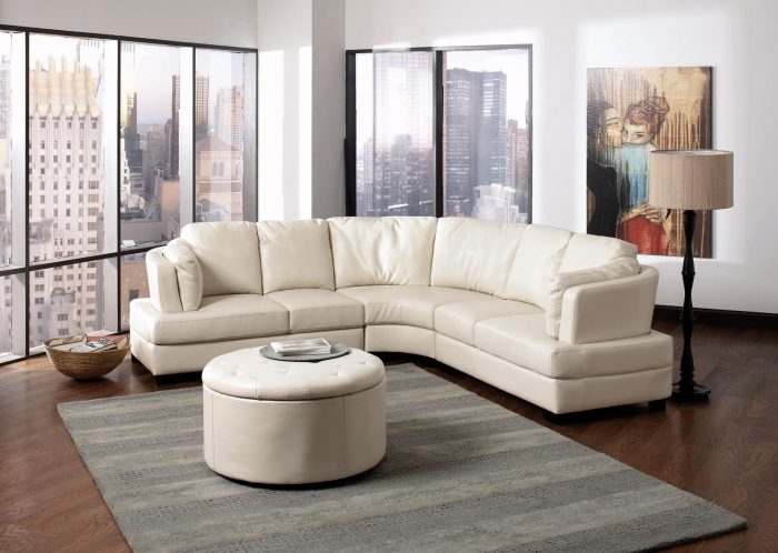 Furniture + Accessories Medium size Simple Living Room Design With ELegance White Leather Sectional Sofa Furniture Set With Unique Table Wipes Simple Rug Laminated Wooden Floor Wall Paint Simple Lamp Wall And Large Window